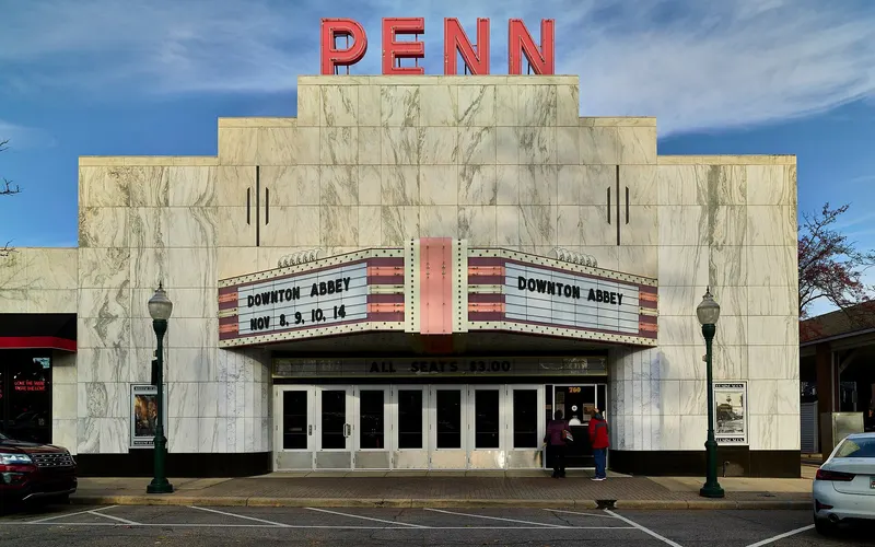 Downtown Plymouth, MI showing Kellogg Park and the historic Penn Theatre marquee with shops and outdoor seating along Main Street