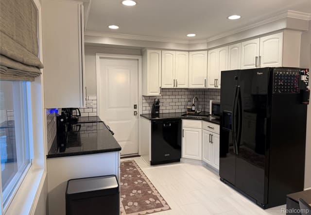 Updated kitchen with white cabinetry, granite counters and black appliances